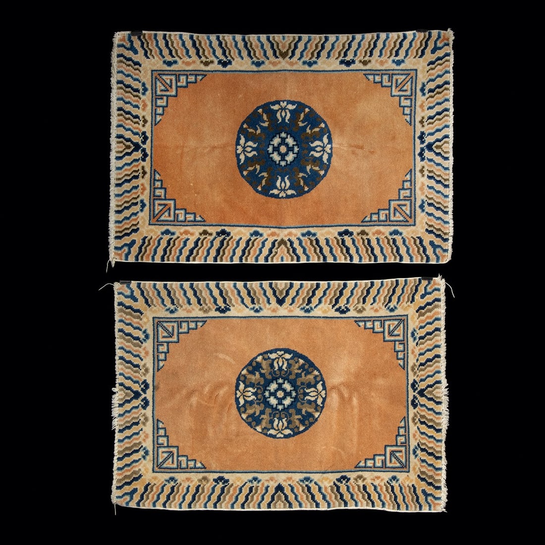 Early 20th C. Peking Chinese Wool Rugs - Pair with Medallions: East Asia, China, ca. early 20th century CE. A pair of Chinese Peking hand-knotted wool mats, each with a round floral medallion in blue, cream, and brown on an open peach field. The spandrels are set