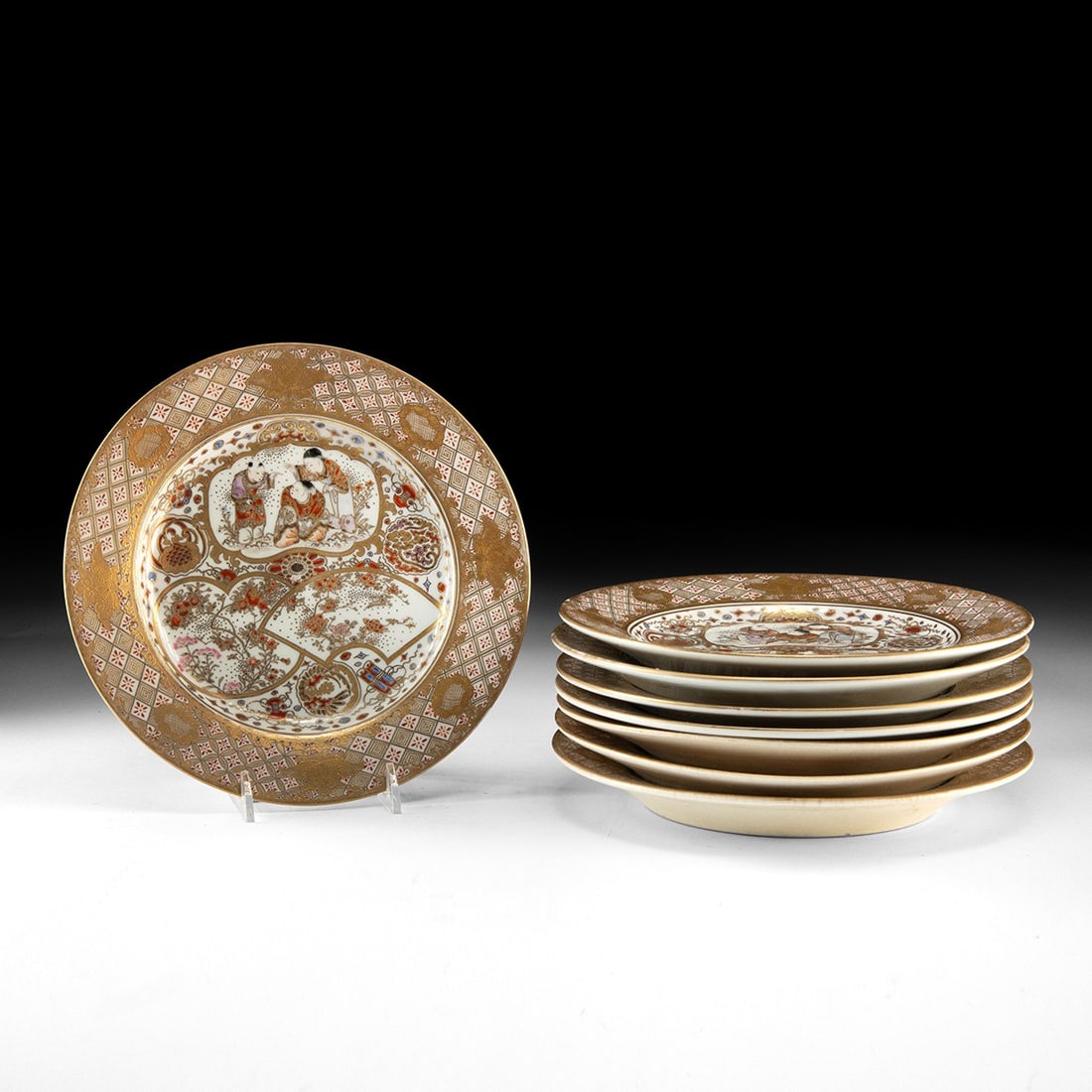 19th C. Japanese Kutani Gilt Porcelain Plates - Figural & Floral, Set of 8: East Asia, Japan, Meiji period, ca. 1868–1912 CE. A set of eight porcelain plates whose cream ground glows beneath a dense lattice of gilt and iron-red diaper work. Each rim carries brocade-styl