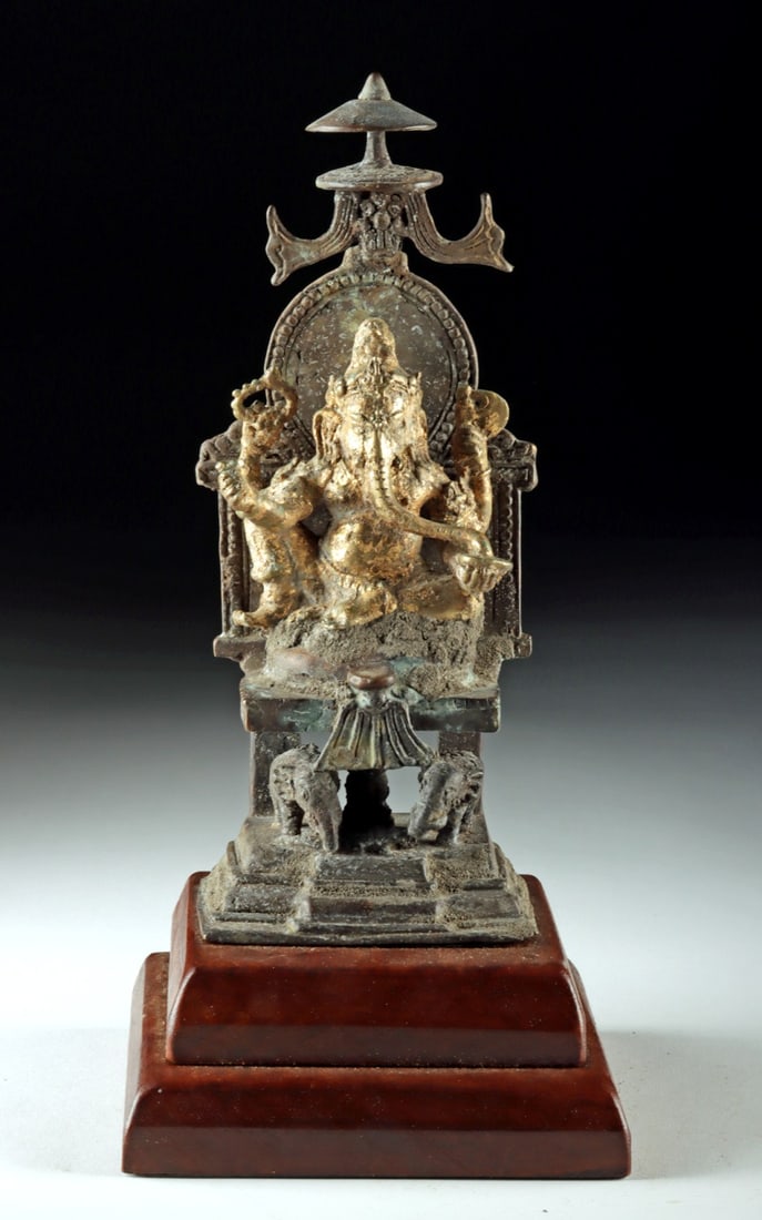 Indonesia (Java) Brass Ganesha - Elephants, Parasol: Southeast Asia, Indonesia, Java, ca. 18th to 19th century CE. A brass statue of the deity Ganesha shown seated in royal ease and set upon a throne beneath a parasol, an iconographic sign of sovereignt