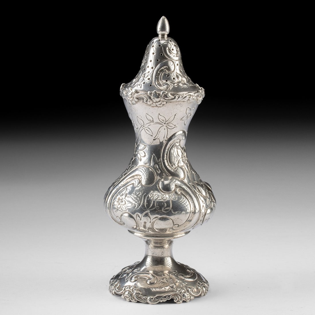 Shreve & Co. Sterling Silver Muffineer - Repousse Floral, HHJ Monogram: North America, United States, California, San Francisco, Shreve & Co. Ca. 1900–1915 CE. A sinuous sugar caster rises on a scrolled, foliate foot to a waisted, hourglass body, its swelling belly 