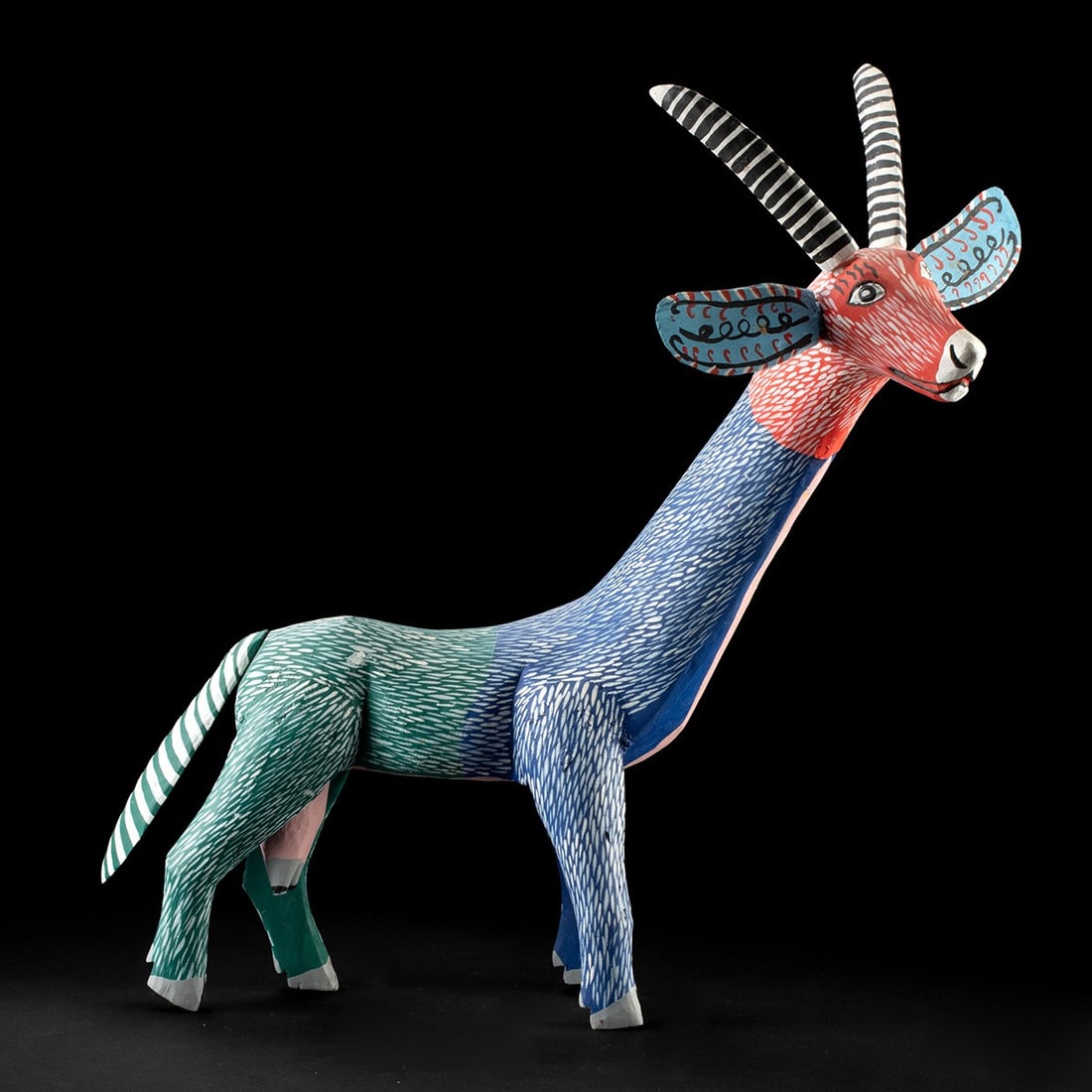 Vibrant Mexican Wood Alebrije Antelope Carving by Martin Fuentes: Mexico, Oaxaca, Zapotec (San Martin Tilcajete), ca. 1980–2010 CE. A hand-carved copal wood alebrije taking the elongated form of a gazelle or antelope, its neck stretched into a graceful curve a