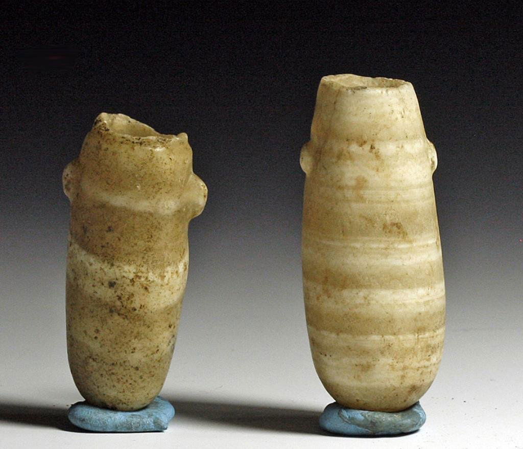 Lot of 2 Egyptian Banded Alabaster Jars: Starts at $300 Egypt, Middle Kingdom, ca. 1985 - 1773 BCE. A pair of finely carved banded alabaster cosmetic jars, long in form with little nub handles on either side. Alabaster alternates between bea
