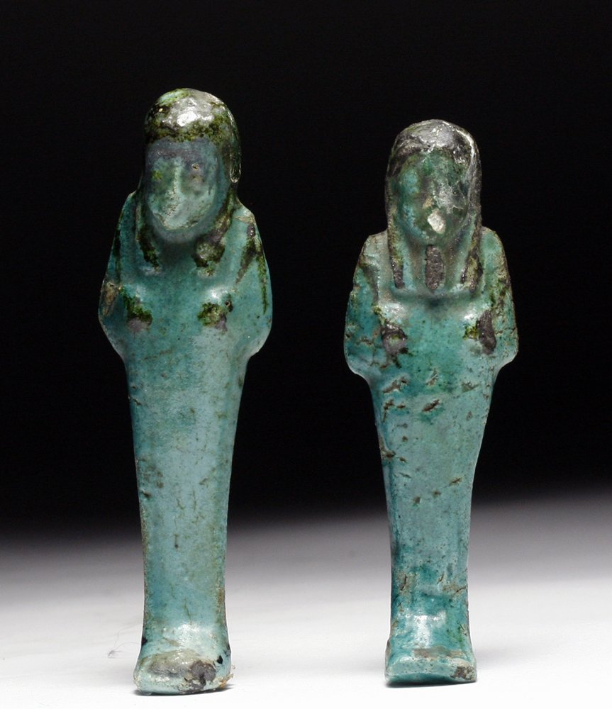 Lot of 2 Egyptian Faience Ushabtis: Starts at $150 Ancient Egypt, Middle Kingdom, ca. 1500 BCE. A set of two faience ushabtis of a teal-blue color with black headdresses. Mummiform figures hold crook and flail across chest. Each just un