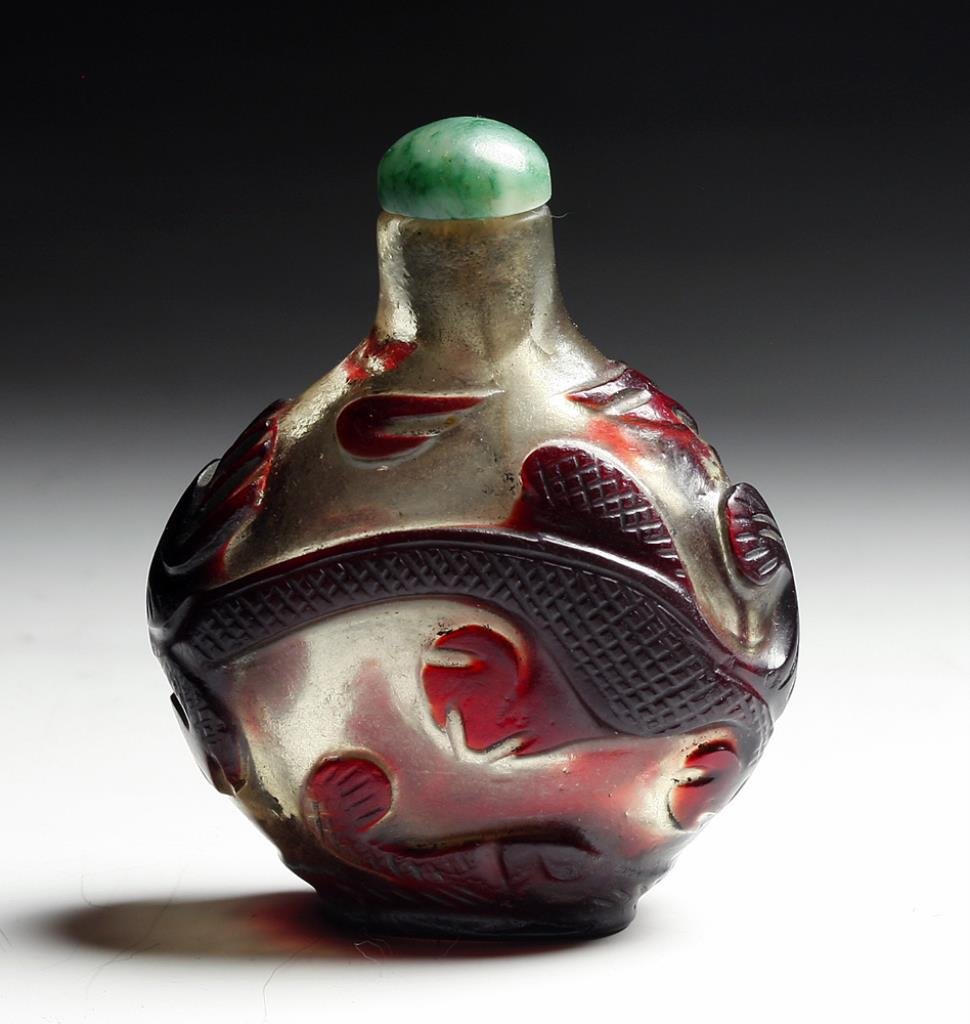Antique Chinese Peking Glass Snuff Bottle, Dragon: Starts at $50 China, late 19th-early 20th century. Clear and deep burgundy red glass carved with an abstract dragon motif. Green jade stopper and bone spoon. 2-1/2"H. Provenance: Ex-Sarkisian collecti