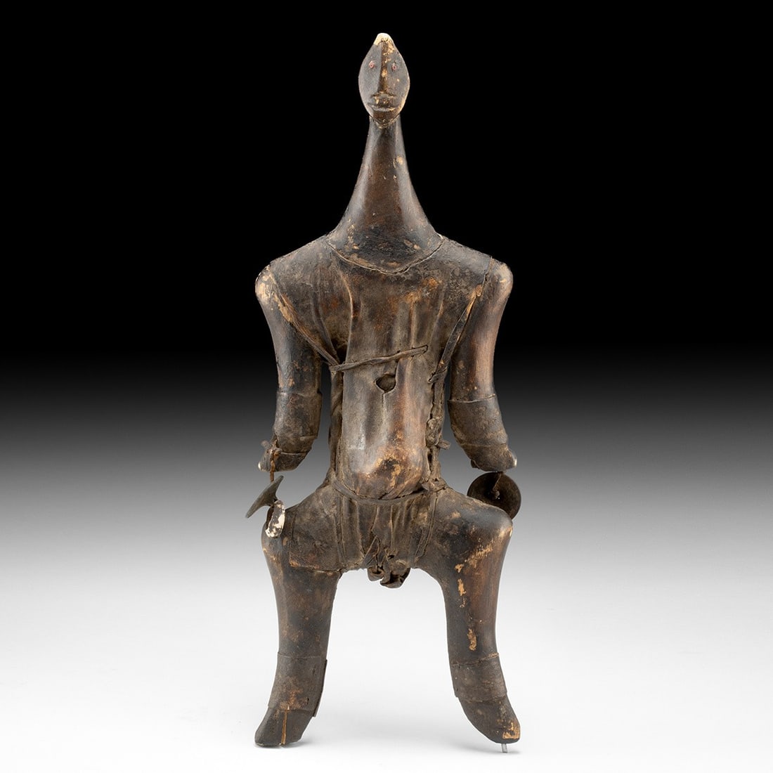 African Namji Wood & Leather Fertility Doll - Cowrie Shell Adornment: Africa, Cameroon, Namji (Dowayo) peoples, ca. mid-20th century CE. A Namji doll from northern Cameroon, the carved wood body sheathed in stitched leather, standing on flexed legs with an elongated nec