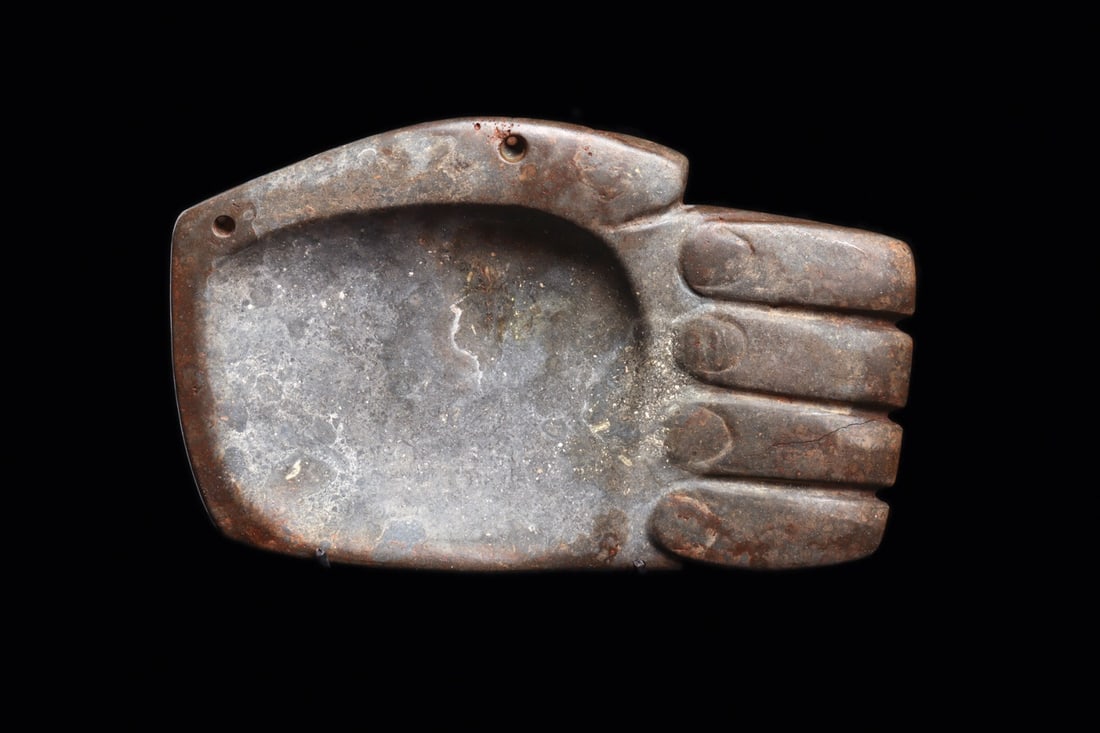 Olmec Serpentine Hand Palette Pectoral with Suspension Holes: Pre-Columbian, Costa Rica, Olmec, ca. 1000–600 BCE. A human hand rendered in gray serpentine, fingers curled inward with the nails crisply indicated and the palm hollowed into a shallow basin. T