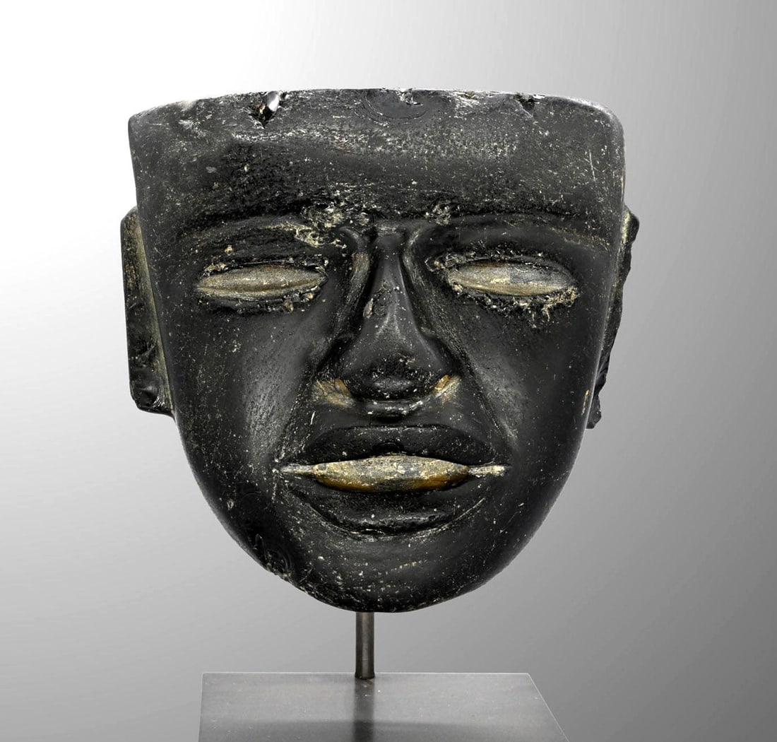 Teotihuacan Obsidian Ceremonial Mask, Ritual Use: Pre-Columbian, Mexico, Teotihuacan, ca. 450–650 CE. A dark, glassy face carved from obsidian, its broad planes rising to a flat brow band and squared crown. The sculptor worked the volcanic glas