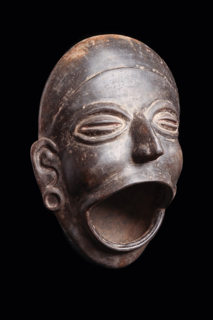 Olmec Blackware Head Vessel with Open Mouth, Cinnabar Traces: Pre-Columbian, Mexico, Olmec regions, ca. 1000–600 BCE. A modeled blackware vessel in the form of a human head, the burnished surface pulled to a lustrous graphite sheen and the mouth thrown wid