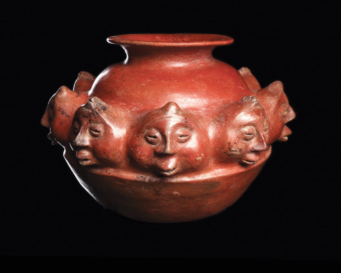 Colima Redware Olla with Nine Modeled Heads: Pre-Columbian, Mexico, Colima, ca. 100 BCE – 250 CE. A squat burnished redware olla, its flaring collar rising from a globular body girdled at the shoulder by nine modeled human heads. Each face