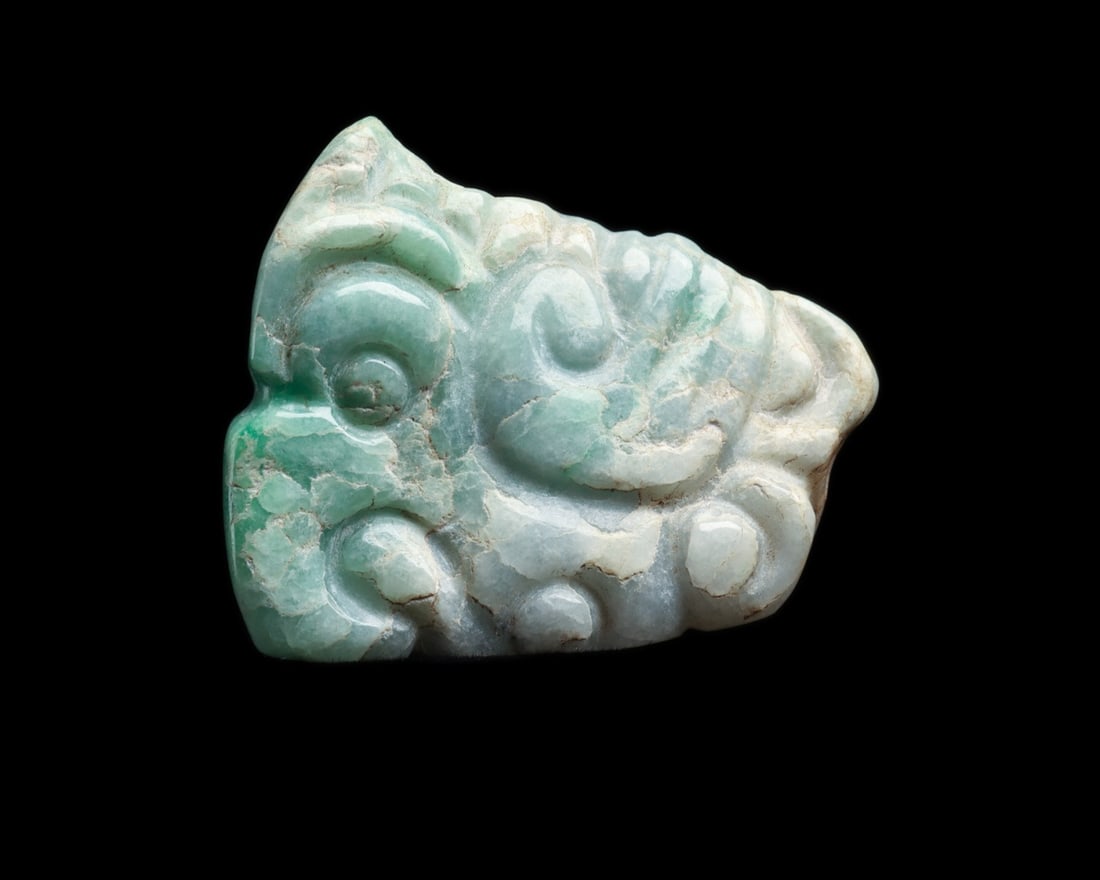 Maya Jade Avian Pendant with Biconical Suspension Holes: Pre-Columbian, Mesoamerica, Maya, ca. 500–800 CE. A carved jade pendant of mottled creamy pale gray and blue-green stone, its front worked in low relief with a stylized bird in profile: a long c