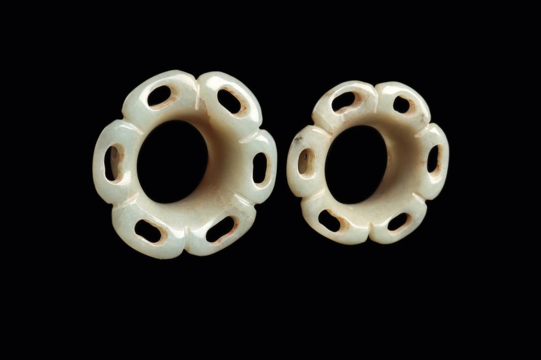 Maya Jade Floral Earspools, Pair: Pre-Columbian, Mesoamerica, Maya, ca. 500–800 CE. A matched pair of pale creamy-green jade earspools, each cut as a six-petalled blossom pierced with openwork perforations around a wide central 