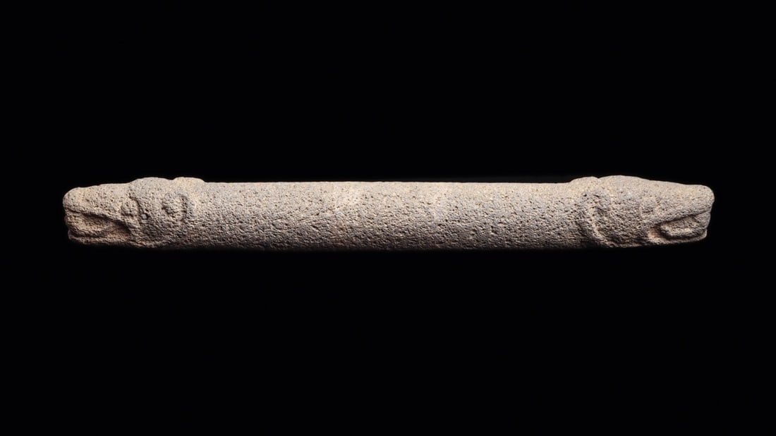Costa Rican Stone Mano with Jaguar Head Finials: Pre-Columbian, Costa Rica, ca. 500–1000 CE. A long baton of gray volcanic stone, pecked and abraded into a slender cylinder and finished at each end with a stylized jaguar head worked in low rel