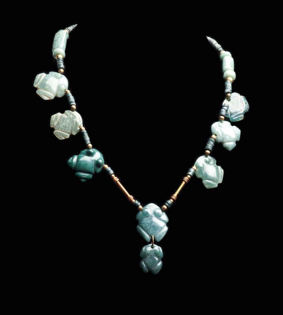 Costa Rican Jade Frog Bead Necklace, 500-1000 CE: Pre-Columbian, Costa Rica, ca. 500–1000 CE. A parade of nine crouching frogs in mottled blue-green jade, each carved flat with a broad head, tucked forelimbs and splayed hind legs, the darkest s