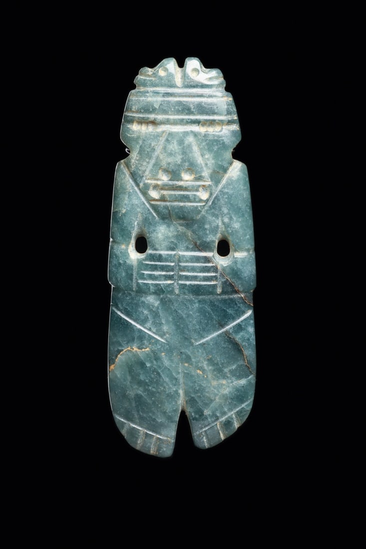 Costa Rican Jade Anthropomorphic Celt Pendant with Double Bird Headdress: Pre-Columbian, Costa Rica, ca. 500–1000 CE. A standing figure emerges from the blade of a polished celt, worked in blue-green jade of mottled translucency. The head wears a wide banded headdress