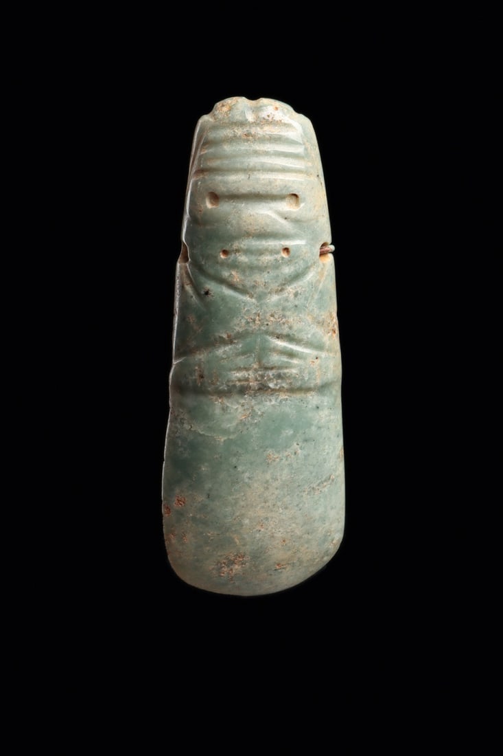 Costa Rica Jade Anthropomorphic Celt Pendant with Goggle Eyes: Pre-Columbian, Costa Rica, ca. 500–1000 CE. A pendant carved from mottled blue-green jade in the form of a standing human, the celt blade itself becoming the body. The head shows a ridged, furro