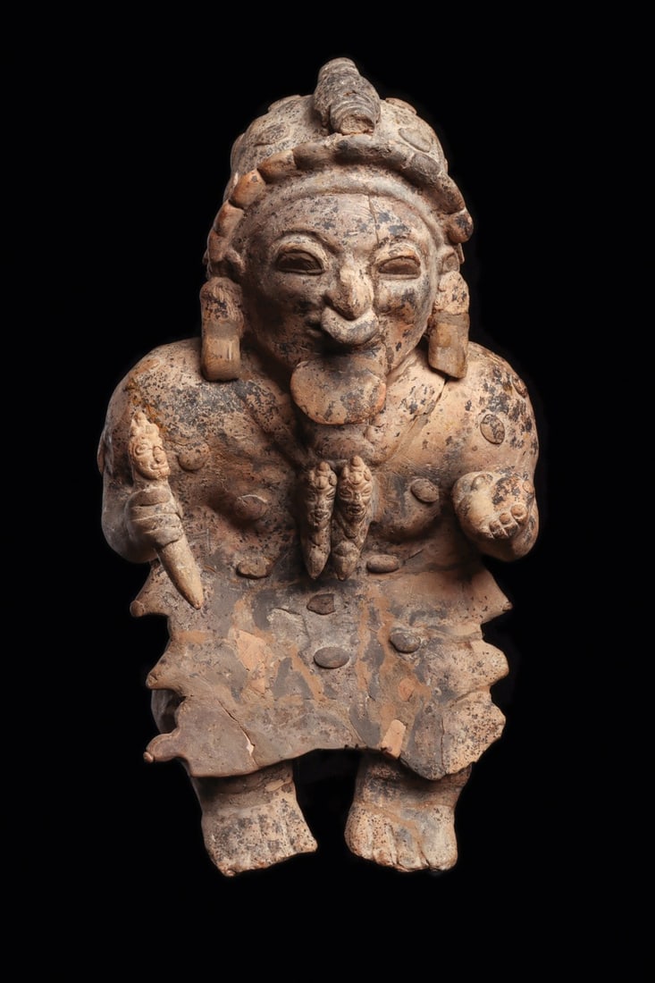 Jamacoaque Large Seated Shaman with Knife and Gourd Vessel: Pre-Columbian, Ecuador, Jamacoaque, ca. 500–1000 CE. A commanding seated dignitary modeled in light salmon-tan pottery, cross-legged beneath a long ceremonial apron. In his right hand he grips a