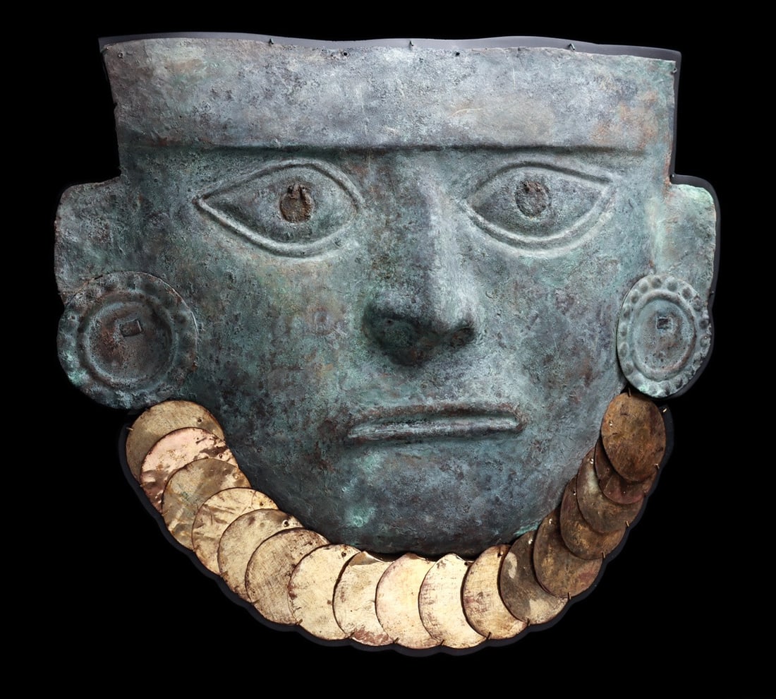 Moche Monumental Funerary Mask of a Lord with Disc Ear Ornaments: Pre-Columbian, Peru, North Coast, Moche, ca. 100–500 CE. A monumental sheet metal mask, hammered and repousse-worked into the broad face of a lord, the brow crossed by a raised headband and the 
