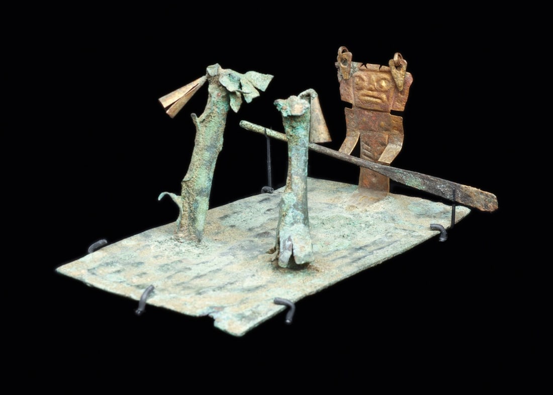Viru Mochica Miniature Raft Tableau with Gilded Standing Oarsman: Pre-Columbian, Peru, Viru-Mochica transitional, North Coast, ca. 300 BCE – 200 CE. A miniature raft in worked sheet metal, its flat deck chased with a low-relief reed pattern in imitation of bou