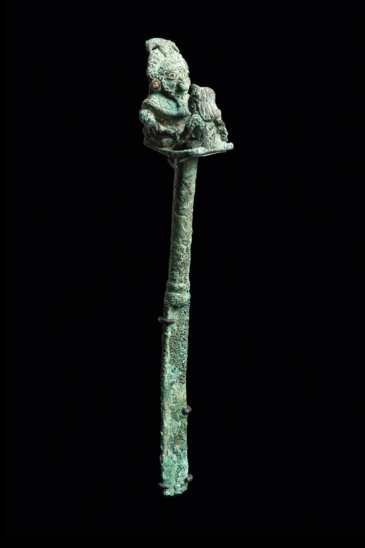 Moche Figural Tumi with Warrior and Bound Prisoner, Loma Negra: Pre-Columbian, Peru, Moche, Loma Negra, 100 CE. A cast copper tumi crowned by a platform finial staging a sacrifice in miniature. The seated warrior or chief wears an elaborate feathered headdress cen