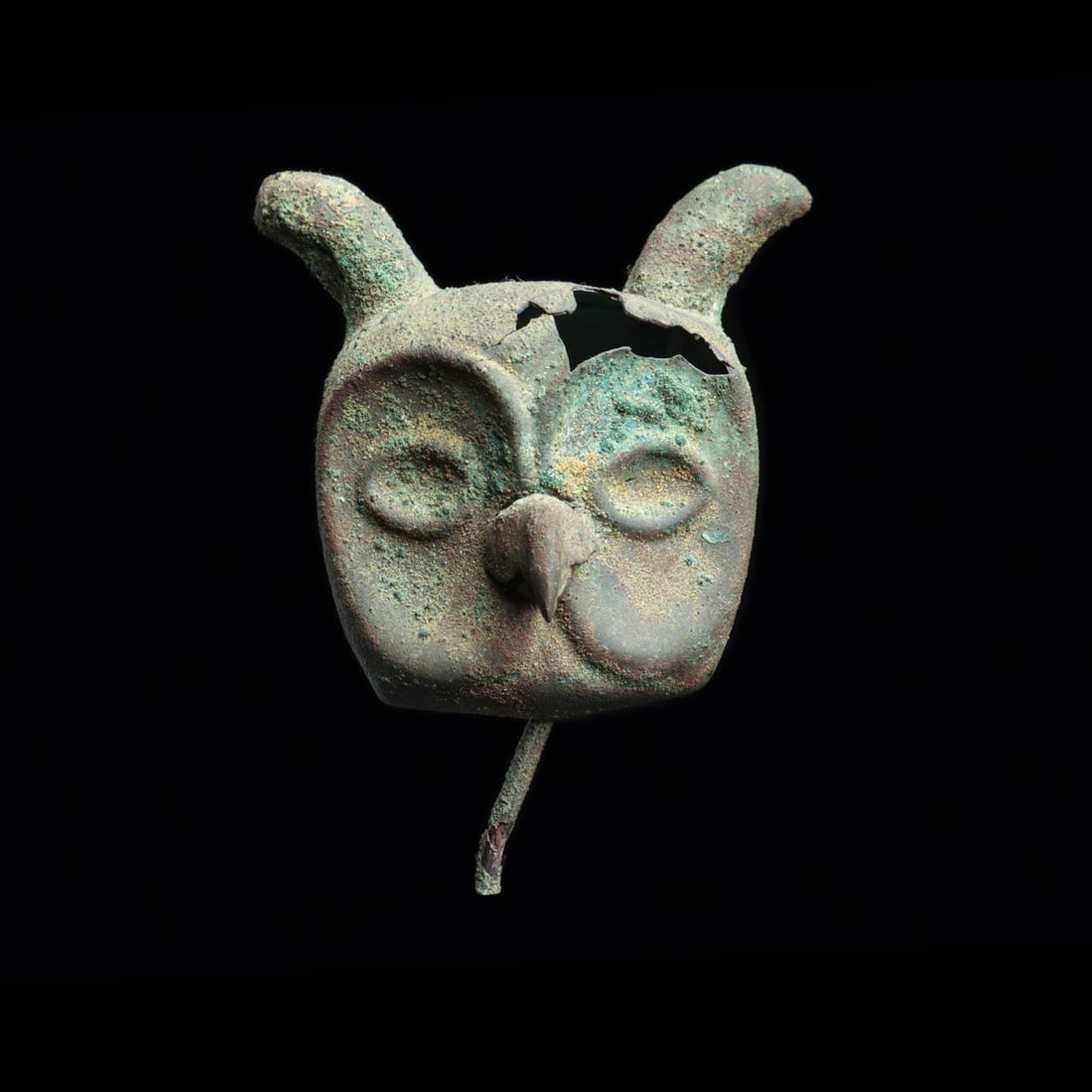 Vicus or Moche Horned Owl Head Votive Ornament with Wire Post: Pre-Columbian, Peru, North Coast, Vicus or Moche, ca. 200 BCE – 200 CE. A horned owl regards the viewer from beneath heavy hammered brows, its head worked in sheet metal over a mold and finished