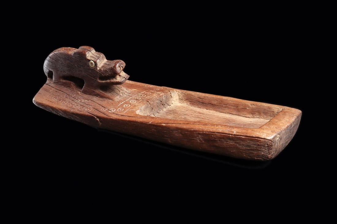 Atacama Snuff Tray with Jaguar Effigy and Shell-Inlaid Eyes: Pre-Columbian, Chile, San Pedro de Atacama, ca. 100–300 CE. A crouching jaguar guards the head of this carved hardwood snuff tray, its tapered rectangular palette hollowed into a shallow recesse