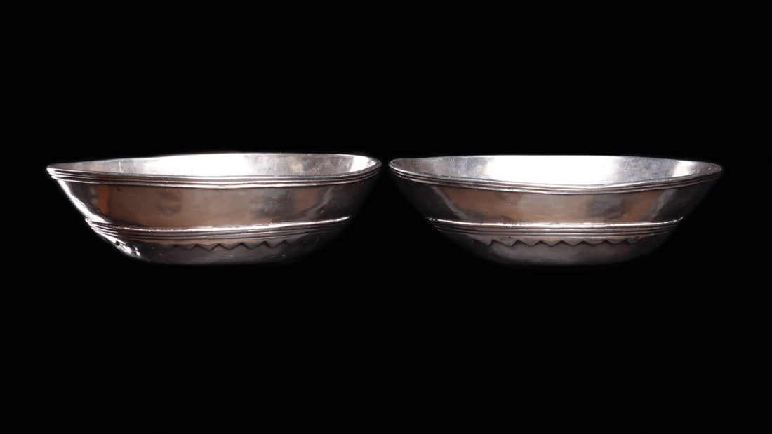 Bolivian Colonial Silver Oval Bowls, Pair, 19th C.: South America, Bolivia, ca. 1800–1899 CE. A matched pair of substantial hand-raised silver bowls, each of shallow oval form with softly canted walls and a thickened, reeded rim. The exterior car