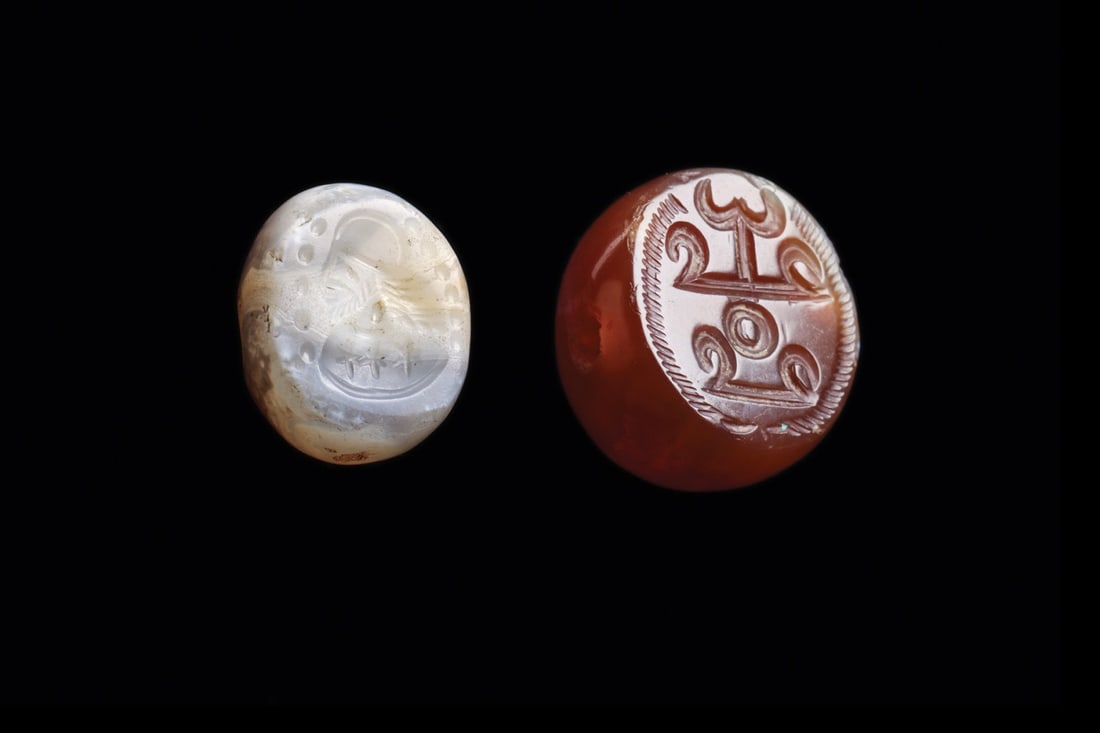 Sasanian Agate Stamp Seals with Royal Bust and Crest, Pair: Western Asia, Sasanian Empire, ca. 400–600 CE. A pair of domed agate stamp seals, each transversely drilled for suspension and cut with an intaglio device on its flattened face. The larger, band