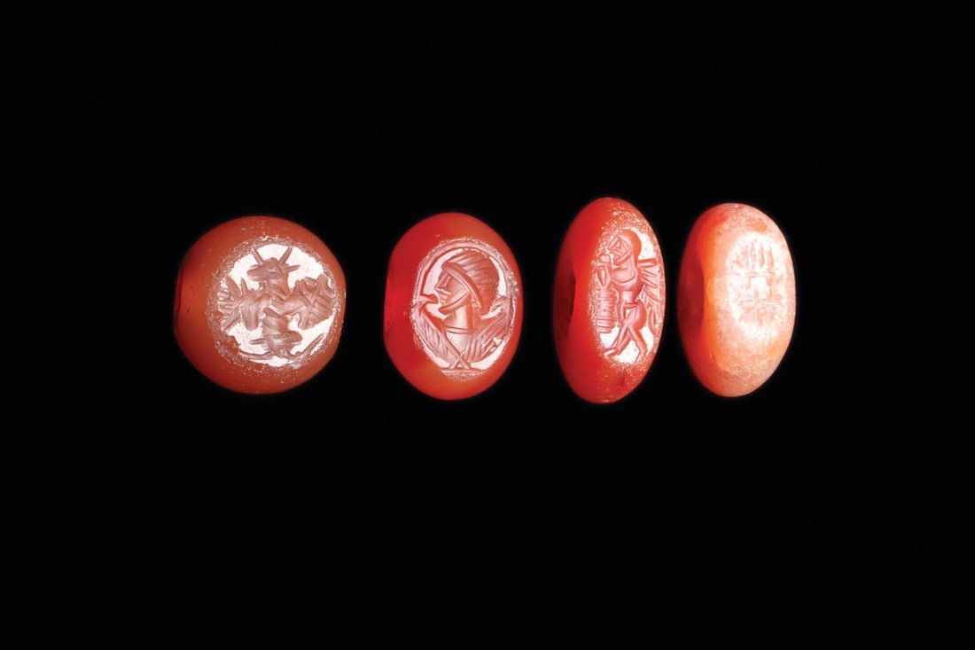 Sasanian Agate Stamp Seals, Group of Four, 5th-6th C.: Western Asia, Sasanian Empire, ca. 400–600 CE. A quartet of domed agate stamp seals in warm red to orange tones, each drilled through the body for suspension and each engraved in intaglio on its