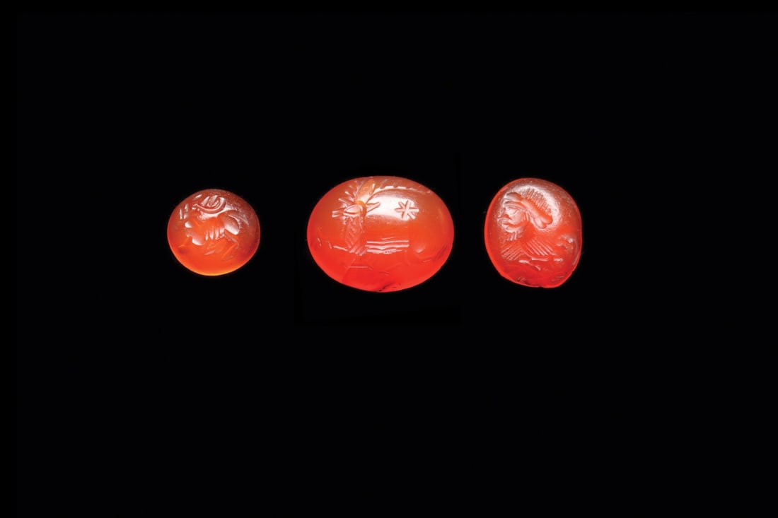 Sasanian Carnelian Intaglio Seals with Stags and Bearded Sphinx, Group of 3: Western Asia, Sasanian Empire, ca. 400–600 CE. A trio of miniature carnelian sealstones, their translucent orange faces cut in intaglio with the crisp wheel work of the late Sasanian gem shops. 