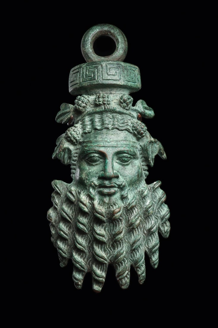 Silen Maskette Counterbalance with Ivy and Grape Diadem, 2nd C. BCE: Magna Graecia, Greek, Hellenistic period, ca. 200–100 BCE. A bearded silen gazes out with unexpected composure, his face framed by a cascade of corkscrew ringlets and lobed side locks worked to 