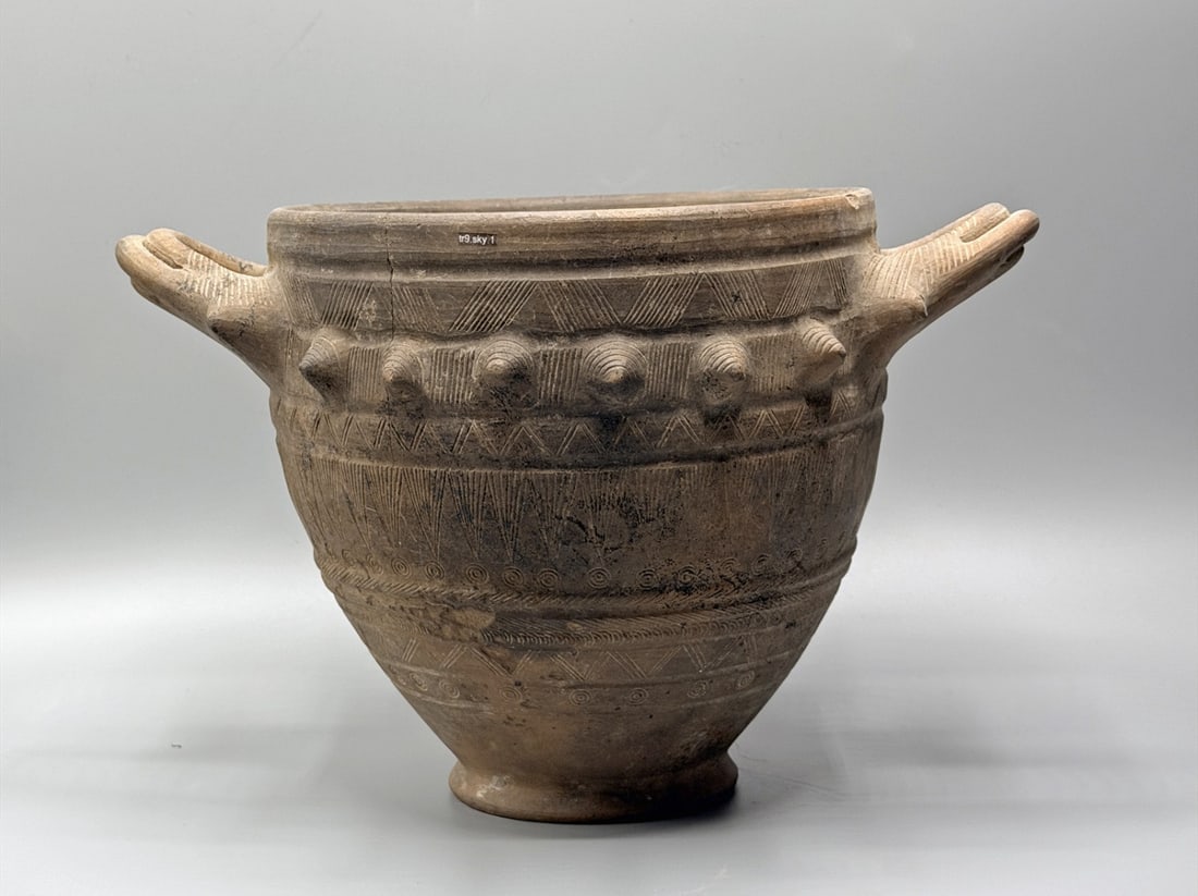 Etruscan Impasto Ware Skyphos, ex-Sotheby's: Etruria, Central Italy, Etruscan, ca. 700–600 BCE. A broad, deep drinking bowl of burnished impasto, its flaring walls rising from a narrow disc foot to a thickened everted rim, flanked by a pai