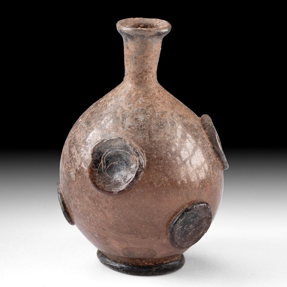 Late Roman Glass Bottle with Blue Prunts, Levant: Eastern Mediterranean, Levant, Late Roman to Early Byzantine, ca. 500–599 CE. A small free-blown glass bottle, with a globular body rising to a narrow neck and an outsplayed rim with a rounded l