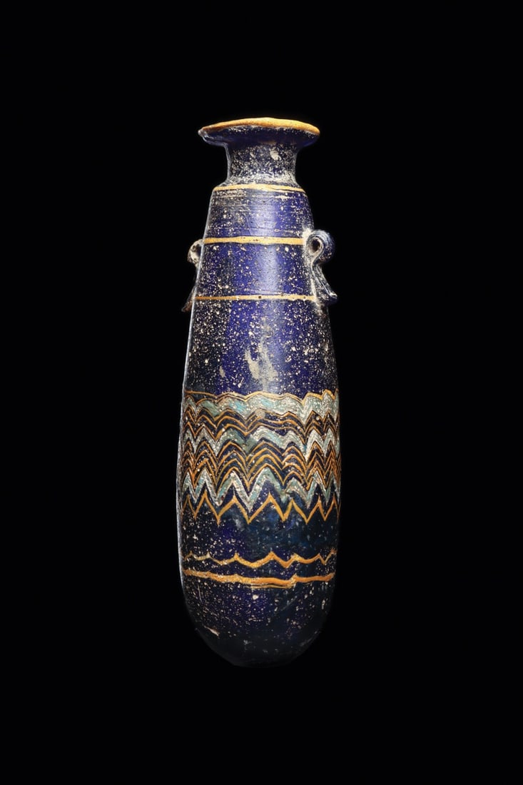 Phoenician Core-Formed Glass Alabastron | Zigzag Trail: Eastern Mediterranean to Near East, Phoenician, ca. 500–200 BCE. A deep cobalt blue core formed alabastron of slender ovoid body rising to a short neck and broad disc rim edged in yellow trailing. T