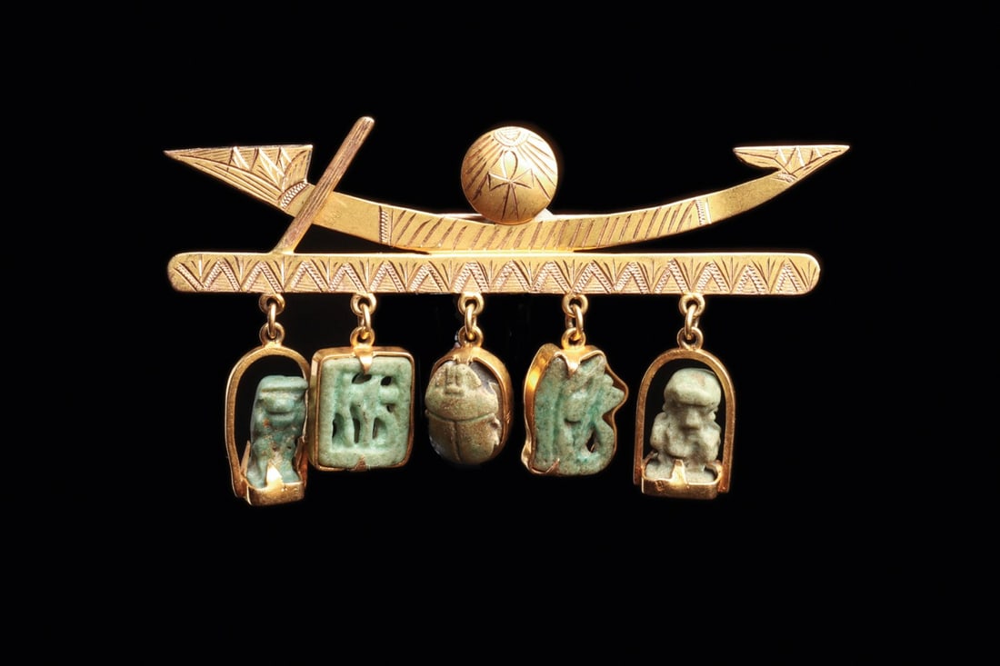 Egyptian Faience Amulet Brooch, Solar Barque with Scarab and Wedjat Danglers: Egypt, Late Period amulets in a modern setting, ca. 700–30 BCE. A custom brooch built around five ancient blue-green glazed faience amulets, suspended as danglers from an engraved bar below a st