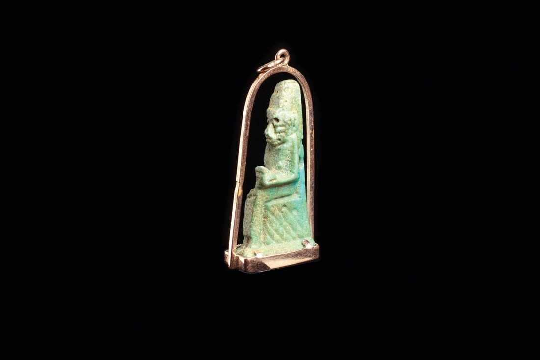 Egyptian Faience Isis Lactans Amulet Pendant, Late Period: Egypt, Late Period, ca. 700–30 BCE. A small blue-green faience amulet of Isis enthroned, the infant Horus cradled across her lap and drawn to her breast. The goddess wears a long sheath and trip