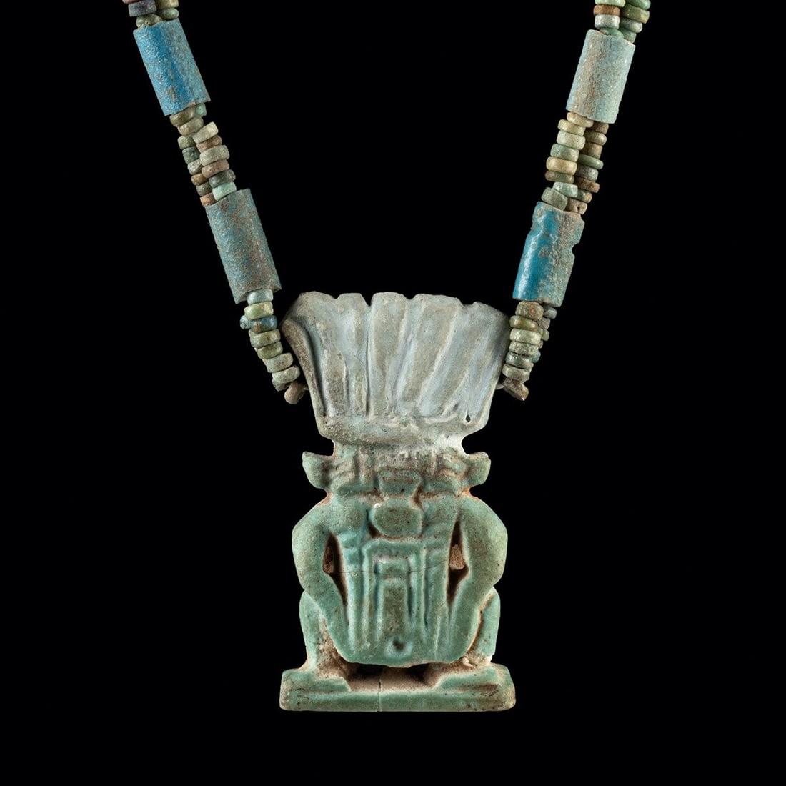 Egyptian Faience Bead Necklace w/ Amulet of Bes, ex-Mitry: North Africa, Egypt, Third Intermediate to Late Dynastic Period, ca. 1069–332 BCE. A pendant amulet of the dwarf-god Bes on a strand of ancient faience beads, the glaze retaining a pale blue-gre