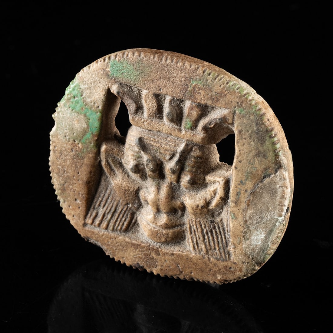 Egyptian Faience Openwork Bes Face Plaque, ex-Mitry: North Africa, Egypt, Third Intermediate Period, ca. 945–712 BCE. A glazed composition plaque, cast in openwork, depicting the face of the dwarf-god Bes framed within a cushion-shaped, beaded bor