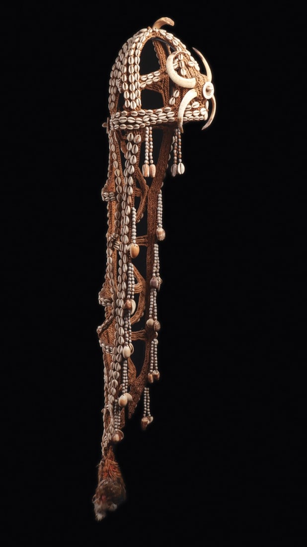 Iatmul Bride Price Headdress "Ambusab" with Cowrie Shells and Boar Tusks: Oceania, Papua New Guinea, Middle Sepik River, Iatmul culture, ca. 1800–1950 CE. A cascading bridal headdress of knotted plant fiber, worked in an openwork net that rises to a domed cap and fall