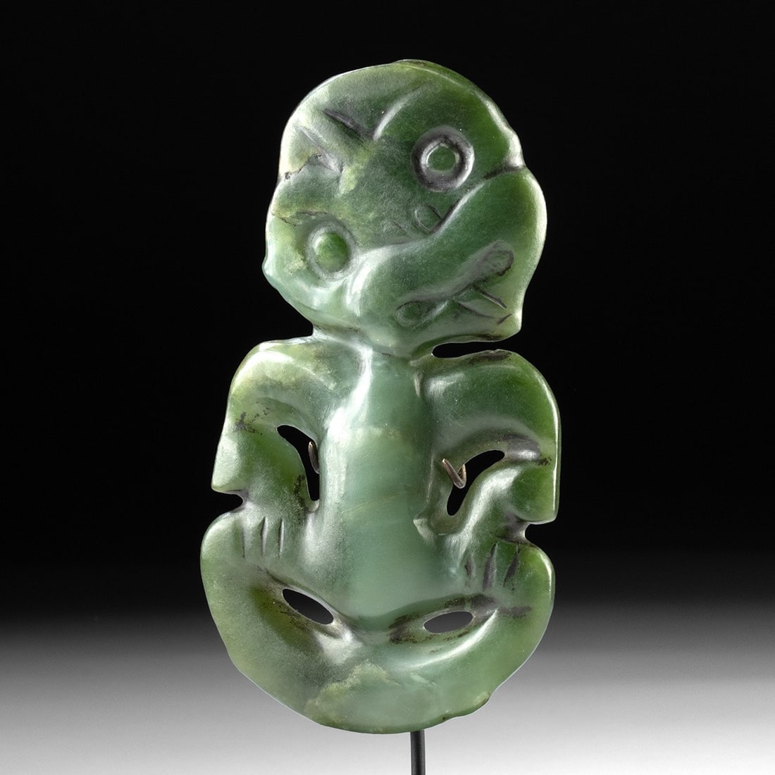 18th C. Maori Jade Hei Tiki, Pounamu: Oceania, New Zealand, Maori. Pounamu (nephrite jade) hei tiki carved into the abstracted human form for which these pendants are famous. The figure's oversized head tilts sharply to the right, its bro