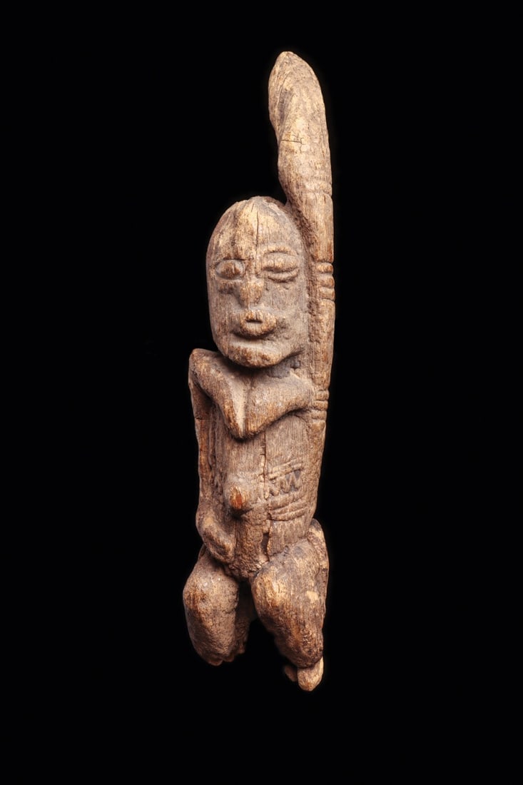 Dogon or Tellem Style Female Figure with Raised Arm, Mali: West Africa, Mali, Dogon or Tellem, ca. 1700–1900 CE. A small standing female carved in dense wood, her left arm thrown vertically above the head in the raised-arm gesture that defines the Bandi