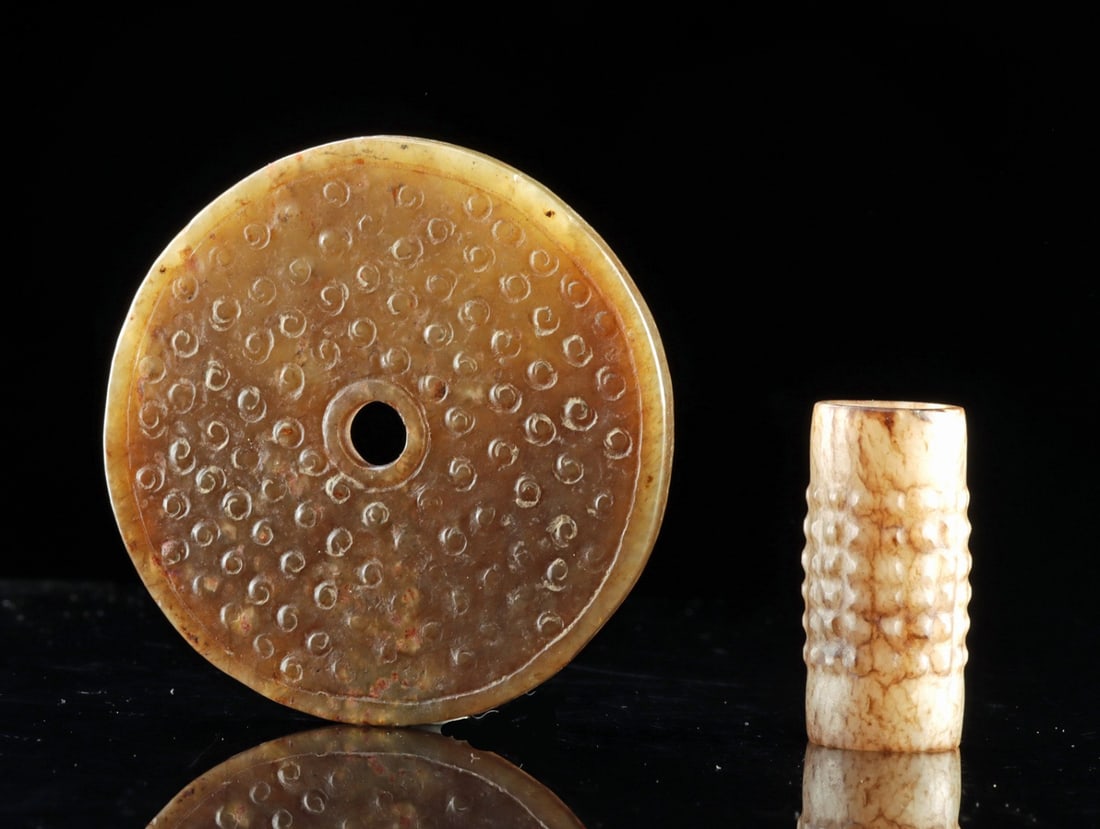 Warring States Nephrite Bi Disc + Ribbed Bead, Guwen Design: Chinese Warring States, ca. 475–221 BCE. A circular disc of nephrite worked to an even section and pierced at the center, its outer edge finished with a raised concentric border band framing the
