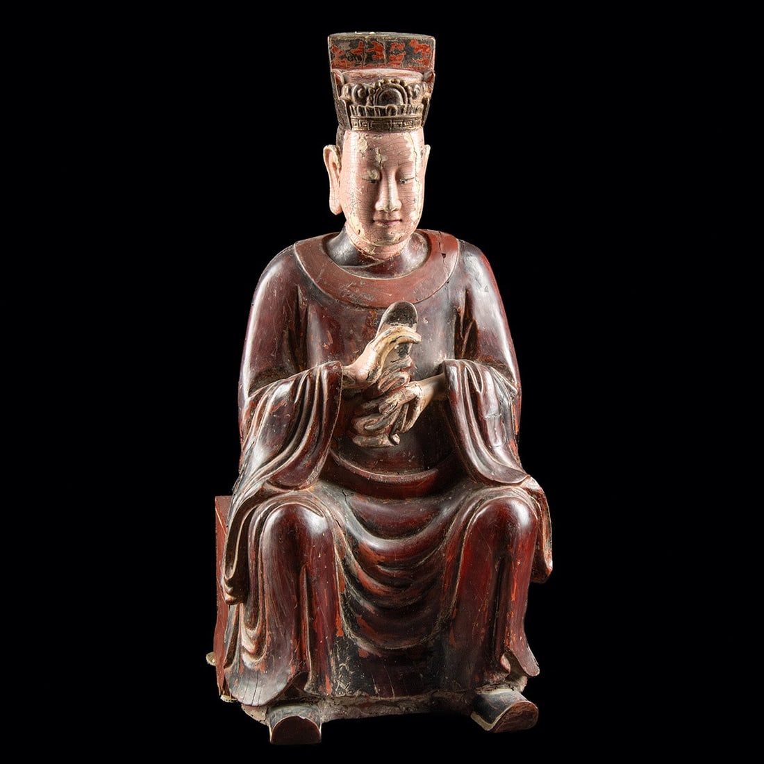 18th C. Chinese Wood Daoist Deity Figure, Oxblood Lacquer: East Asia, China, Qing Dynasty, ca. 1700–1799 CE. A carved wood figure of a seated Daoist deity, finished in oxblood lacquer across the folds of a high-collared robe. The figure is seated in a forma