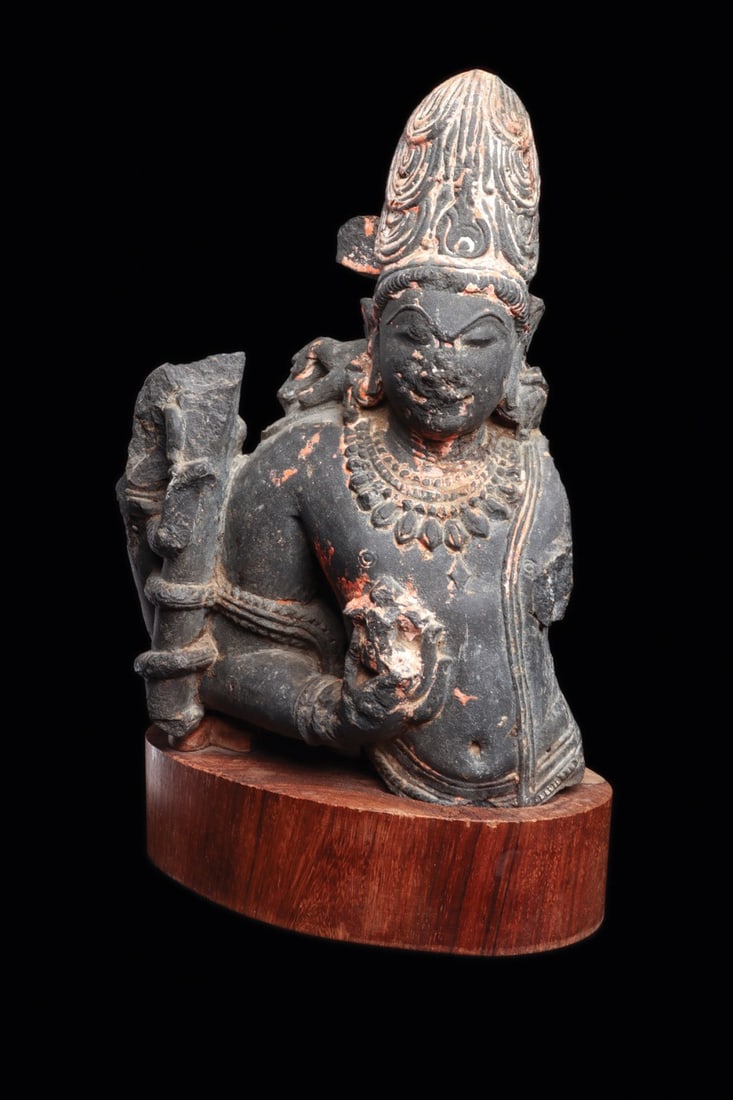Ellora Style Schist Bust of a Prince or Deity with Lotus, 10th C.: South Asia, India, Ellora style, ca. 900–1000 CE. A crowned figure emerges from the broken stone with the composure of a temple deity, carved in gray-black schist and preserved from the waist up