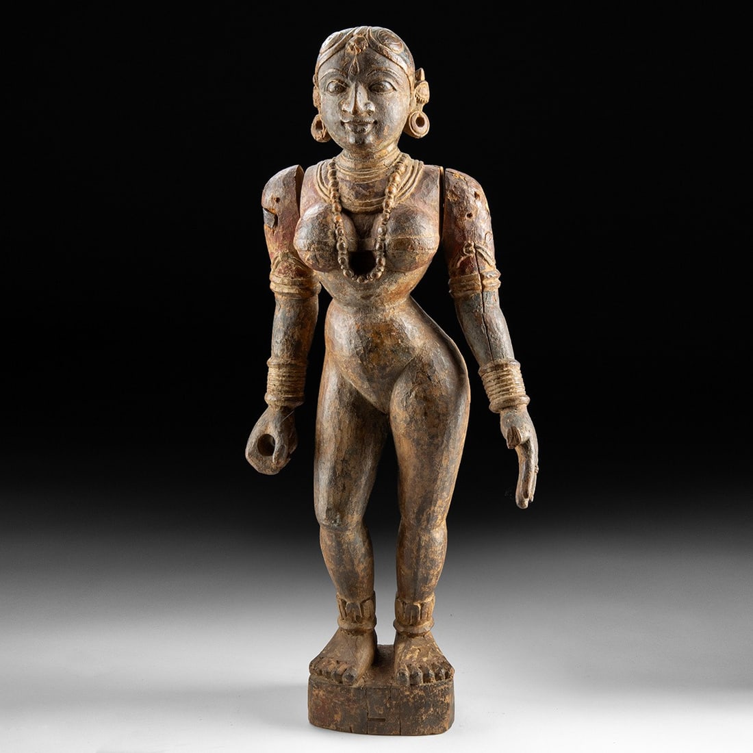 19th C. Indian Wood Devi Figure, Articulated Arms, Tamil Nadu: South Asia, India, Tamil Nadu, ca. 1800–1899 CE. A standing female divinity carved from wood, her softly modeled body rising nude but for lavish ornament: a tiered beaded torque descends between
