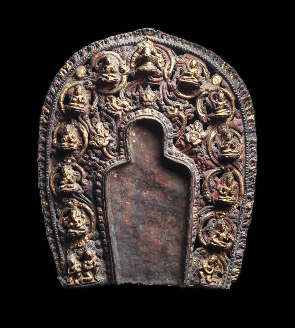 Nepalese Repousse Aureole with Twelve Deities, 14th C.: South Asia, Nepal, Newar tradition, ca. 1300–1400 CE. A hammered and repousse copper aureole (prabhamandala) built to stand behind a Buddha image, its arched openwork field pierced into scrollin