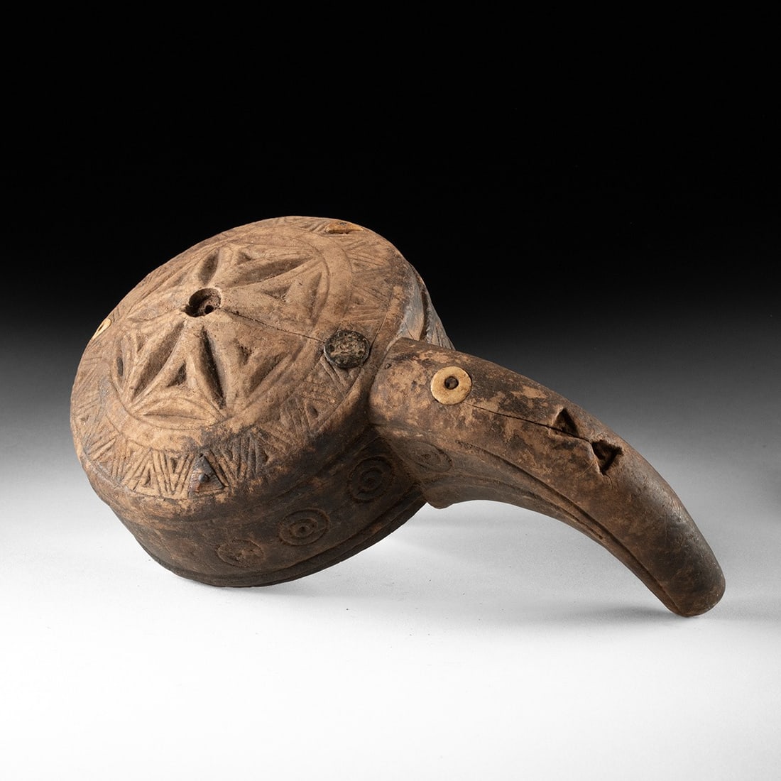 Ottoman Carved Wood Gunpowder Flask w/ Shell Inlay: Near East, Ottoman Empire, ca. 1800–1899 CE. A gunpowder flask carved from mocha-hued wood, its body swelling into a broad crescent that tapers to an upswept spout pierced for the charge. The ex