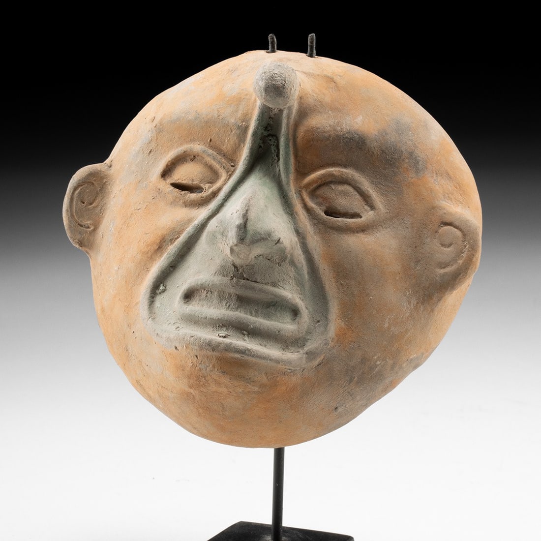 Jamacoaque Maskette with Forehead Knob, Ecuador, Ca. 300 BCE - 400 CE: Pre-Columbian, Ecuador, Jamacoaque, ca. 300 BCE – 400 CE. A broad, moon-round face modeled in buff earthenware, its features pressed and pinched into an expression of drowsy inwardness. The eyes