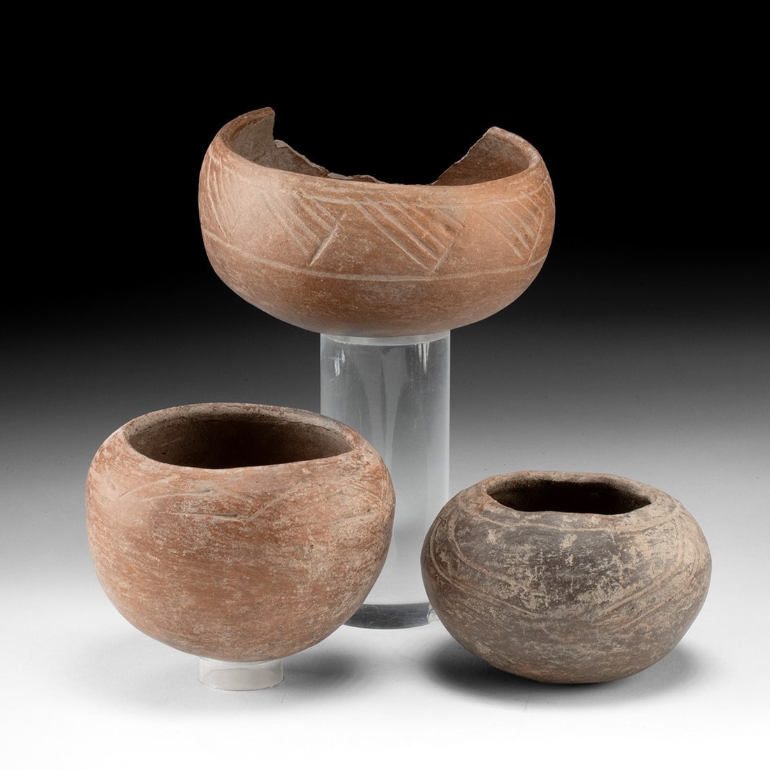Three Nicoya Incised Redware Bowls: Pre-Columbian, Costa Rica, Nicoya (Greater Nicoya, Guanacaste), ca. 1000–1500 CE. A trio of hand-built earthenware bowls, each a compressed globe of burnished buff-to-terracotta clay, the walls