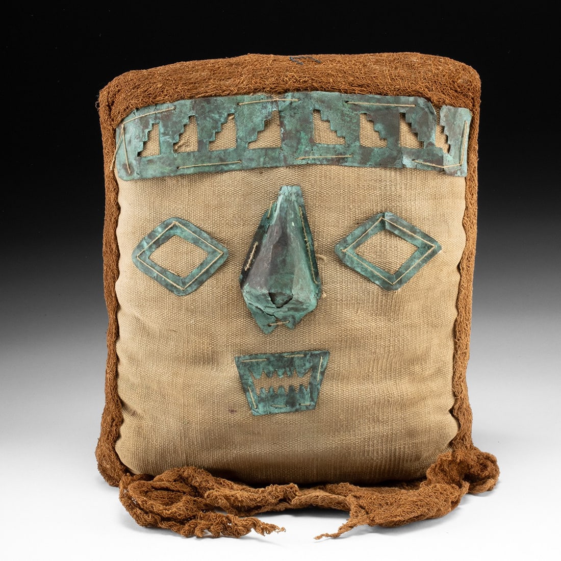 Chancay False Head Funerary Mask w/ Copper Facial Appliques: Pre-Columbian, Peru, Chancay, ca. 1000–1470 CE. A woven face gazes out from a plain-weave cotton panel, its features cut from sheet copper and stitched directly to the cloth. Lozenge-shaped
