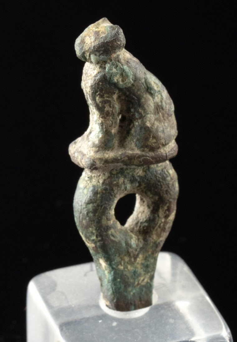 Egyptian Leaded Bronze Bastet Cat Ring-Loop Finial: Ca. 664–30 BCE. Ancient Egypt, Late Dynastic to Ptolemaic Period, ca. 664 to 30 BCE. A small leaded-bronze cat finial, modeled in an upright seated pose with the tail curling to the right, rises